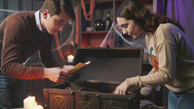 Friends Searching for Clues in Halloween Themed Escape Room Wooden Chest to Solve Mystery Puzzle Game