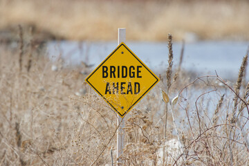 A sign on the bank of the river announcing the proximity of the bridge