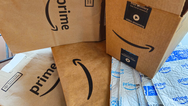 Amazon Prime packaging materials, including a cardboard box, paper bags used for grocery delivery, and plastic bubble mailers (Minneapolis, USA - Jan. 14, 2026). Editorial Use Only.