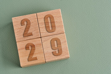 Wooden cube with number 2029 on green background, new year concept.