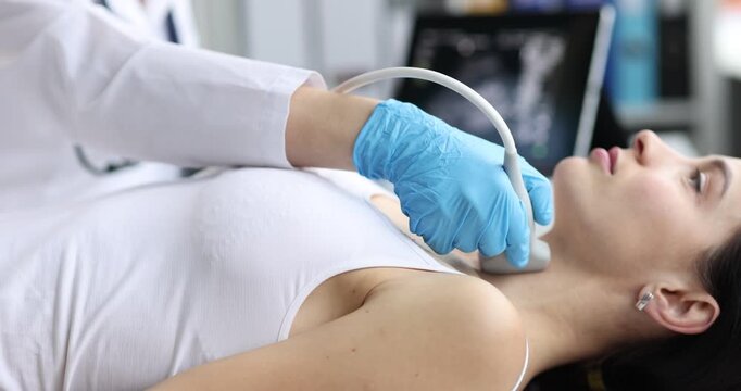 Woman doctor in gloves presses ultrasound probe to neck. Patient lies on examination couch as medical specialist checks thyroid health at appointment