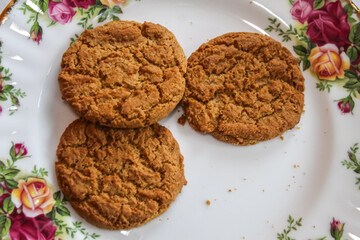 Ginger snap or molasses flavored cookies arranged on a vintage-style floral plate. Cozy tea time or holiday dessert background.
