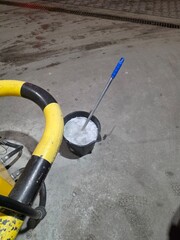 Bucket filled with water and a mop resting on the floor of a commercial space with yellow and black safety barrier visible in the background during cleaning operations