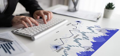 A businessperson focuses on financial data analysis with graphs and charts displayed on the workspace, showcasing modern office equipment and efficiency. Scalp