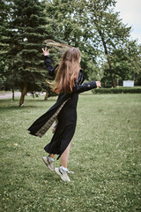 Young woman jumping joyfully in green park with flowing hair
