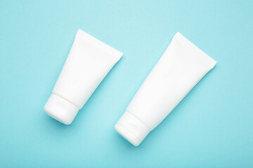 White plastic cosmetic tubes on blue background. Space for text