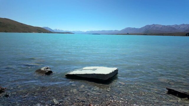 Turquoise Lake Water With Rock At Shore And Mountain Range