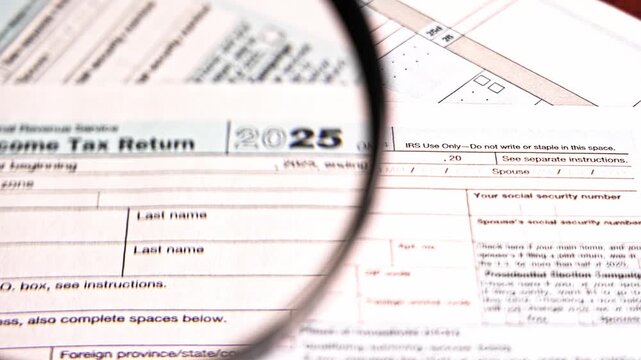 Magnifying glass moving over a united states irs tax return form for the year 2025
