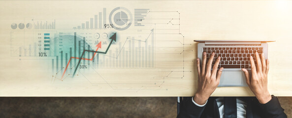 Aerial view of hands typing on a laptop, surrounded by digital graphs and charts representing business growth, analysis, and technology in a modern workspace. Scalp