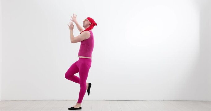 Funny man in pink costume dances in empty studio room. Energetic dancer waves arms while stepping forward with playful rhythmic groove slow motion