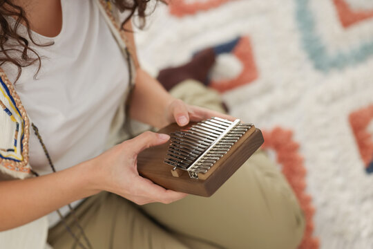 Woman playing kalimba at home, closeup. Space for text