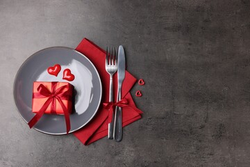 Elegant table setting with gift on grey background, flat lay. Space for text