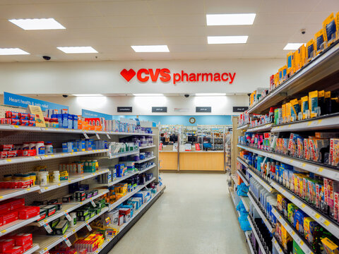 New Hartford, NY - Dec 28, 2025: CVS Pharmacy interior aisle with stocked shelves leading to the prescription counter, featuring health products and service signage
