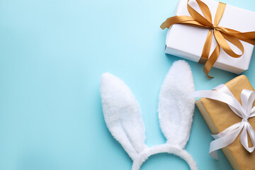 Happy Easter. Cute bunny ears and gift boxes on light blue background, flat lay. Space for text