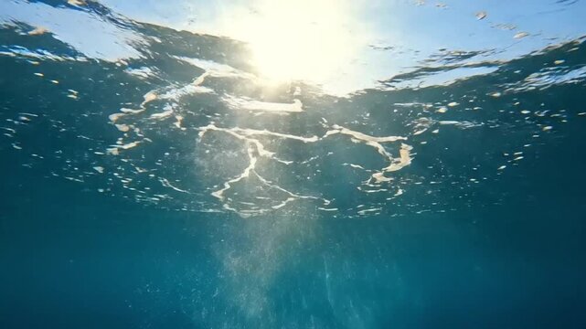 Bubbles rising underwater with sunlight beams, deep blue ocean scene representing diving or surfacing