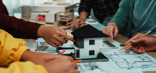 This image captures a collaborative design session where architects engage with a miniature house...