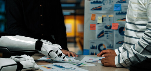 A human and a robotic arm collaborate in a business environment, reviewing market data and...