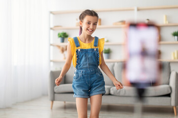 Gen Z Vlogger. Portrait of happy teenager girl filming video for social media, dancing and live...