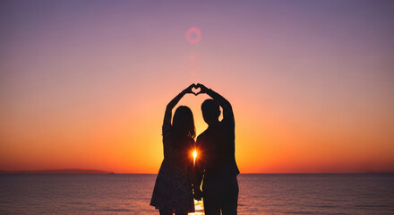Silhouette of Couple Making Heart Shape with Hands at Sunset.