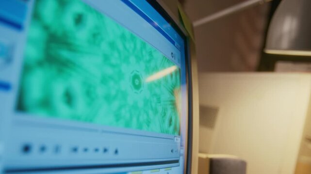No people close-up of anonymous 90s vintage desktop computer user playing audio file with music using mp3 player software with green fractal visualization for entertainment