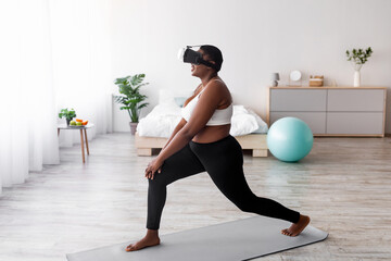 Obraz premium Side view of overweight black lady in VR headset training with virtual reality app, making lunges at home. Plus size Afro woman using modern technologies for online domestic training, full length
