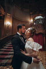 Couple embraces in elegant setting during evening event at historic venue