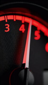 A close-up shot of a car's illuminated dashboard gauge with a red needle pointing to the number four, indicating speed or engine revolutions.
