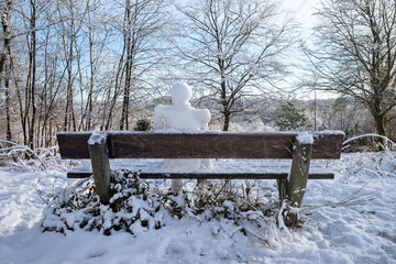 humanoid snowman sitting on a bench