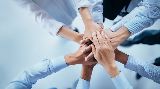 Hyperrealistic premium commercial stock photo of a stack of hands showing unity and teamwork, top-down overhead view of multiple business people placing hands together in the cente