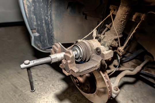 Pressing the brake piston in using a specialized piston retraction tool.