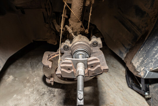 Pressing the brake piston in using a specialized piston retraction tool.