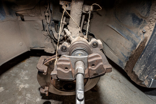 Pressing the brake piston in using a specialized piston retraction tool.
