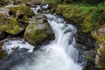 Long exposure of a waterfall on the East Lyn river flowing through the woods at Watersmeet in Exmoor National Park