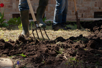 Two people are digging earthen plot in front of  house