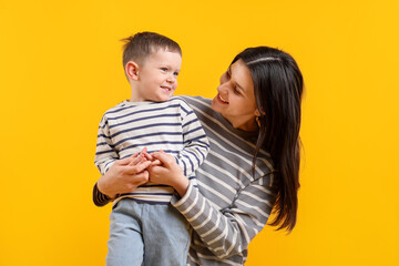 Happy mother hugging her son on yellow background