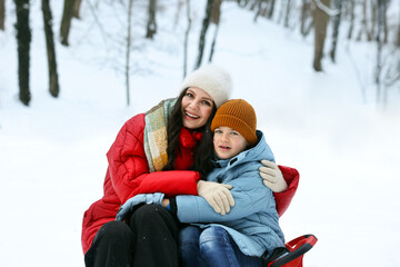 Obraz premium Happy mother and her son with sledge outdoors on winter day