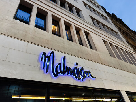 Malmaison hotel sign on a modern Manchester building exterior at dusk