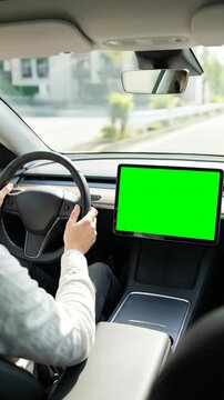 A driver holds the steering wheel while a car drives on a highway with a green screen dashboard display. Concept of automotive technology and navigation. Vertical video