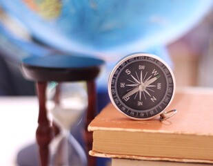 Compass book anf sand glass symbols of knowledge travel finding way and time concept photo	
