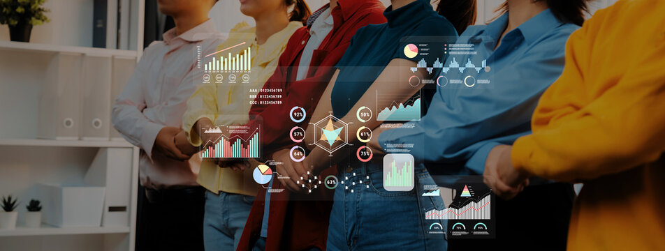 A group of professionals stands together in a modern office, showcasing teamwork and collaboration while engaging with interactive data charts that represent growth and strategy. Trope - Powered by Adobe