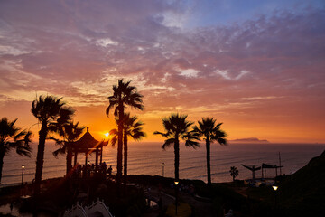 Obraz premium pure magic with a romantic sunset over the Pacific Ocean in Miraflores, Lima. This breathtaking view from the Malecón captures the sun dipping below the horizon, Parque Chino