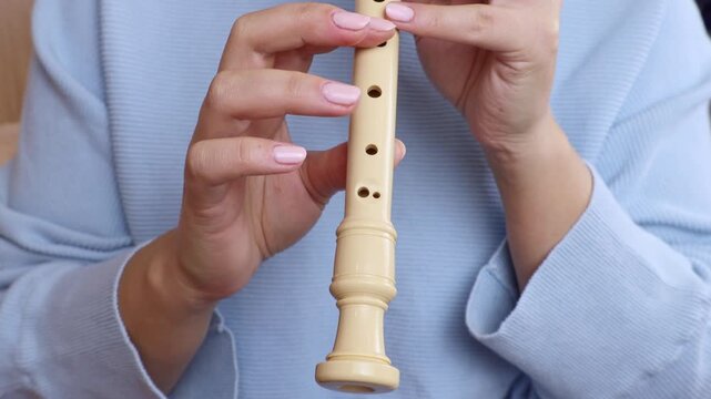 Woman holding in her hands and playing block flute (recorder) musical instrument