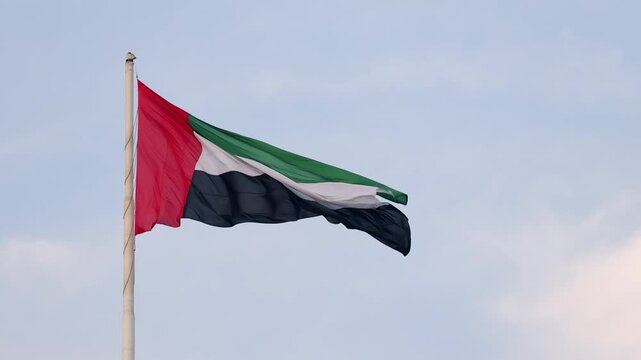 UAE flag waving in the blue sky, national symbol of UAE