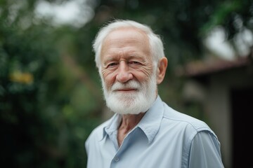 Portrait of a smiling elderly man with a white beard and blue shirt outdoors