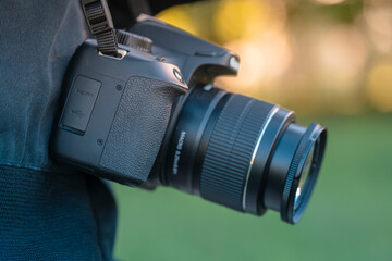 Close-up of Digital SLR Camera with Professional Lens Hanging on a Neck Strap of a Person