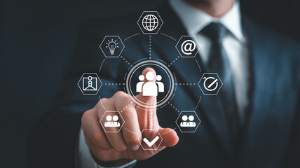 Businessman interacting with virtual human icon in futuristic digital interface with icons and checkmark in blue tone for corporate technology