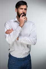 Fototapeta premium Portrait of a man is standing confident looking at the camera and thinking wearing a white shirt in front of a plain white background in a working environment