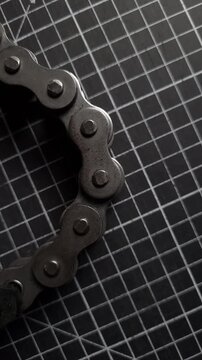 loop of a metal roller chain on a black cutting mat, top view, close-up.