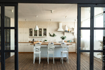 Modern dining room and kitchen interior with table and chairs, big window and wooden floor....