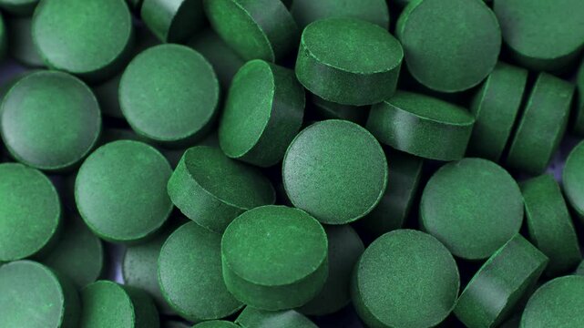 Chlorella or spirulina algae green powder pills circle rotation close up. Dietary supplement to improve health. Seaweed superfood. Healthy food background. Vitamins and minerals to diet detox